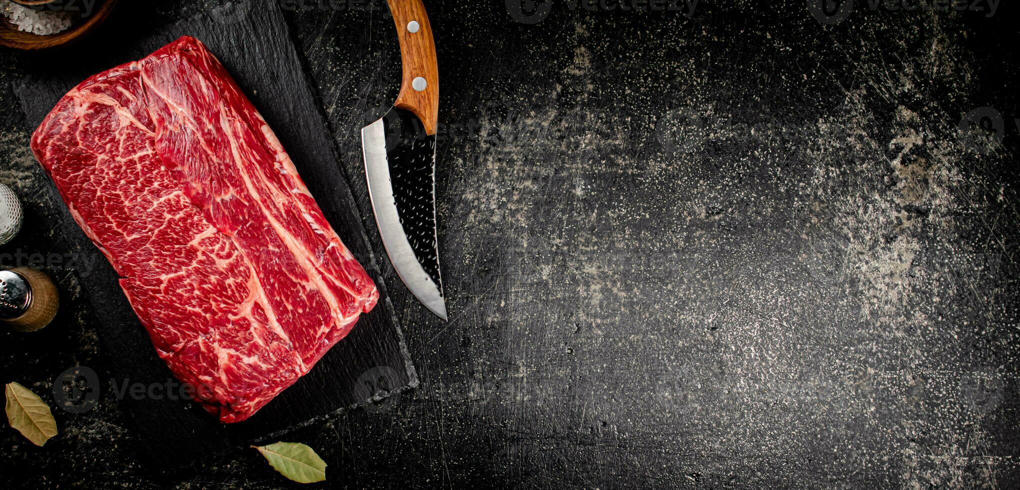 Raw beef on a stone board with a knife. photo