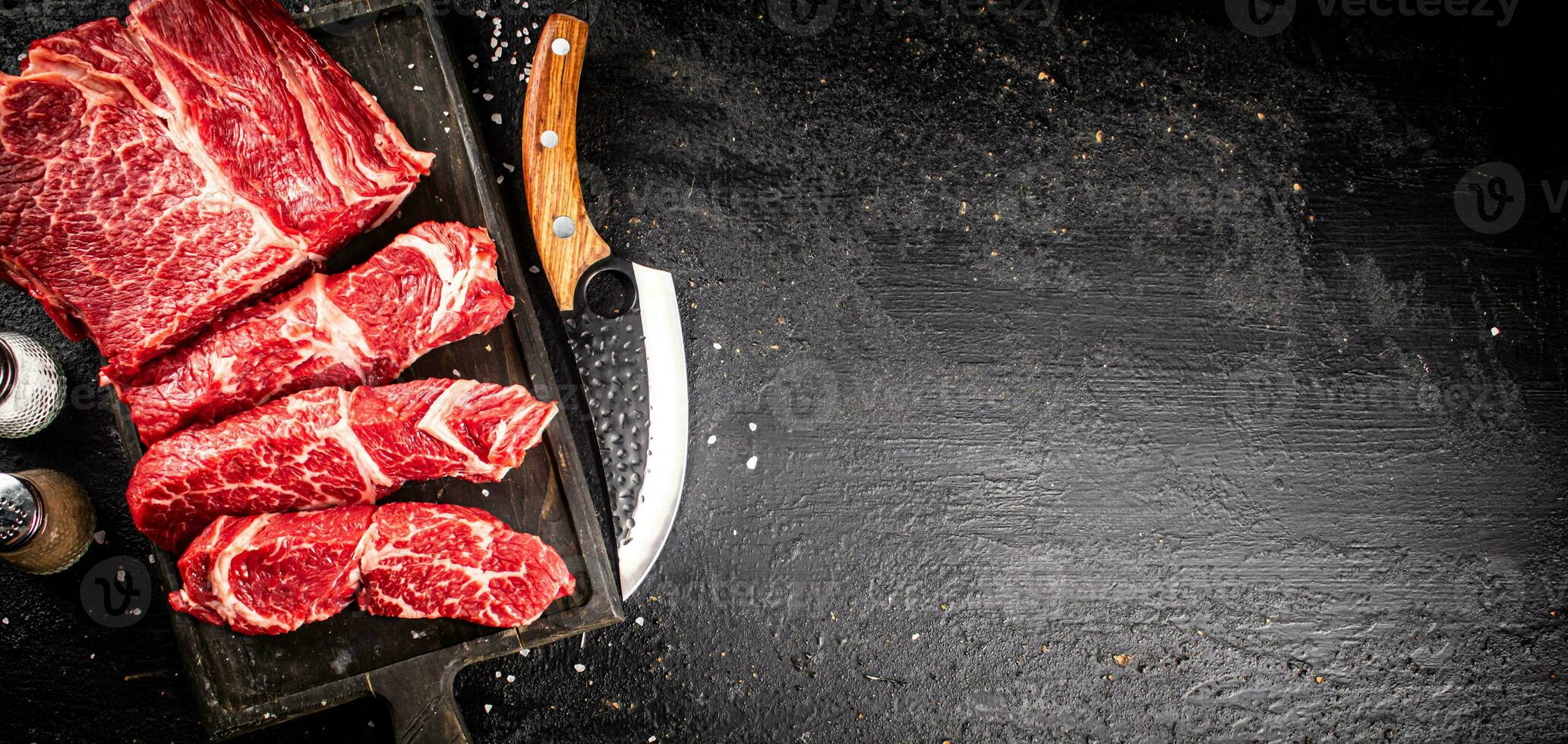 Raw beef on a cutting board with a knife. photo