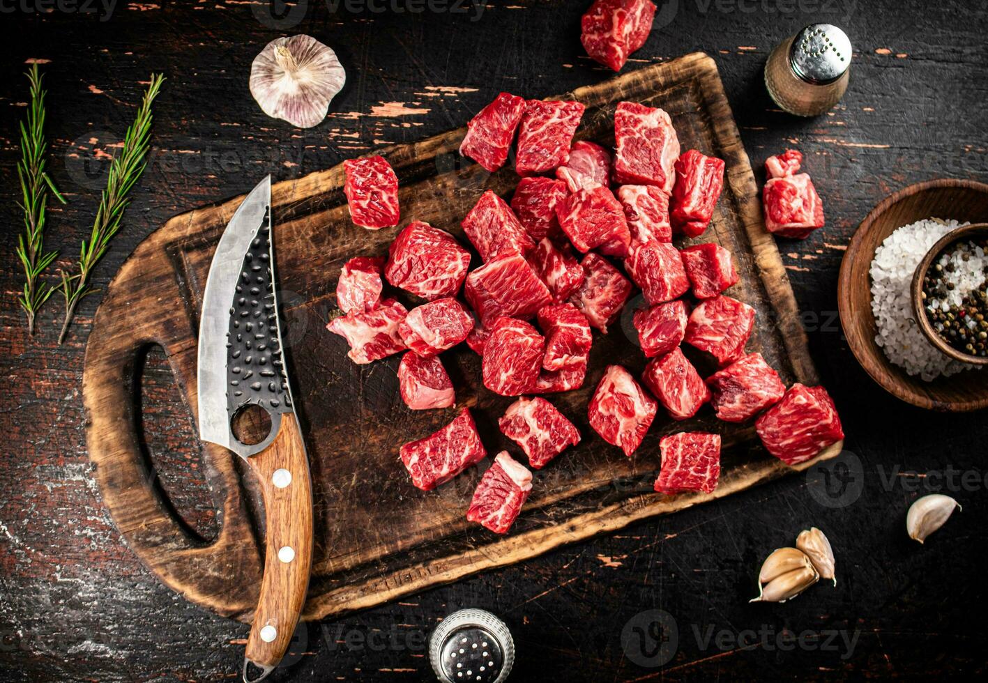 Raw pieces of beef on a cutting board with a knife. photo