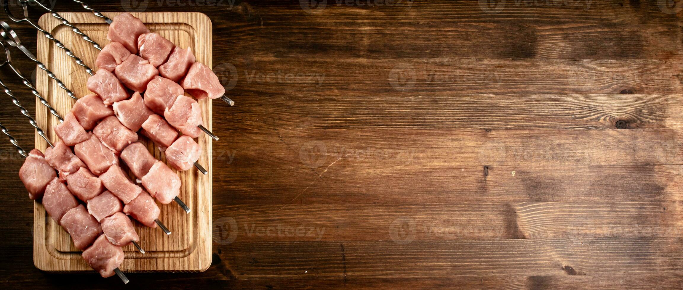 Pork kebab raw on skewers on a cutting board. photo