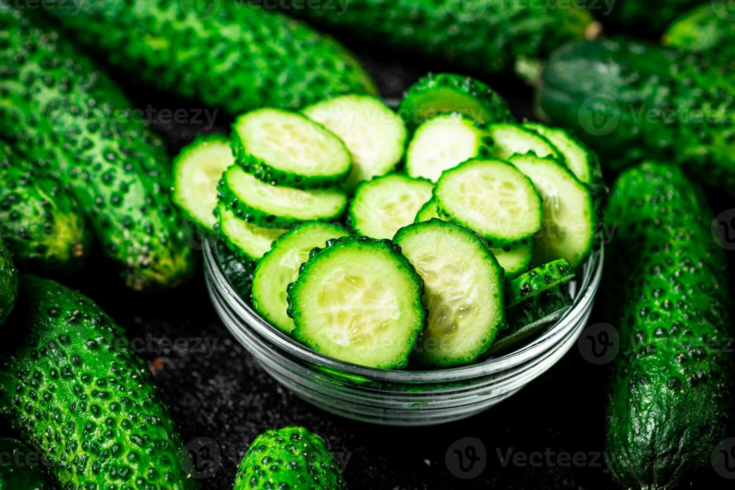 Sliced and whole cucumbers on the table. photo