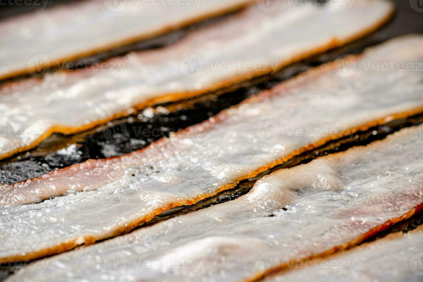 Pieces of bacon are fried in boiling oil with air bubbles. photo