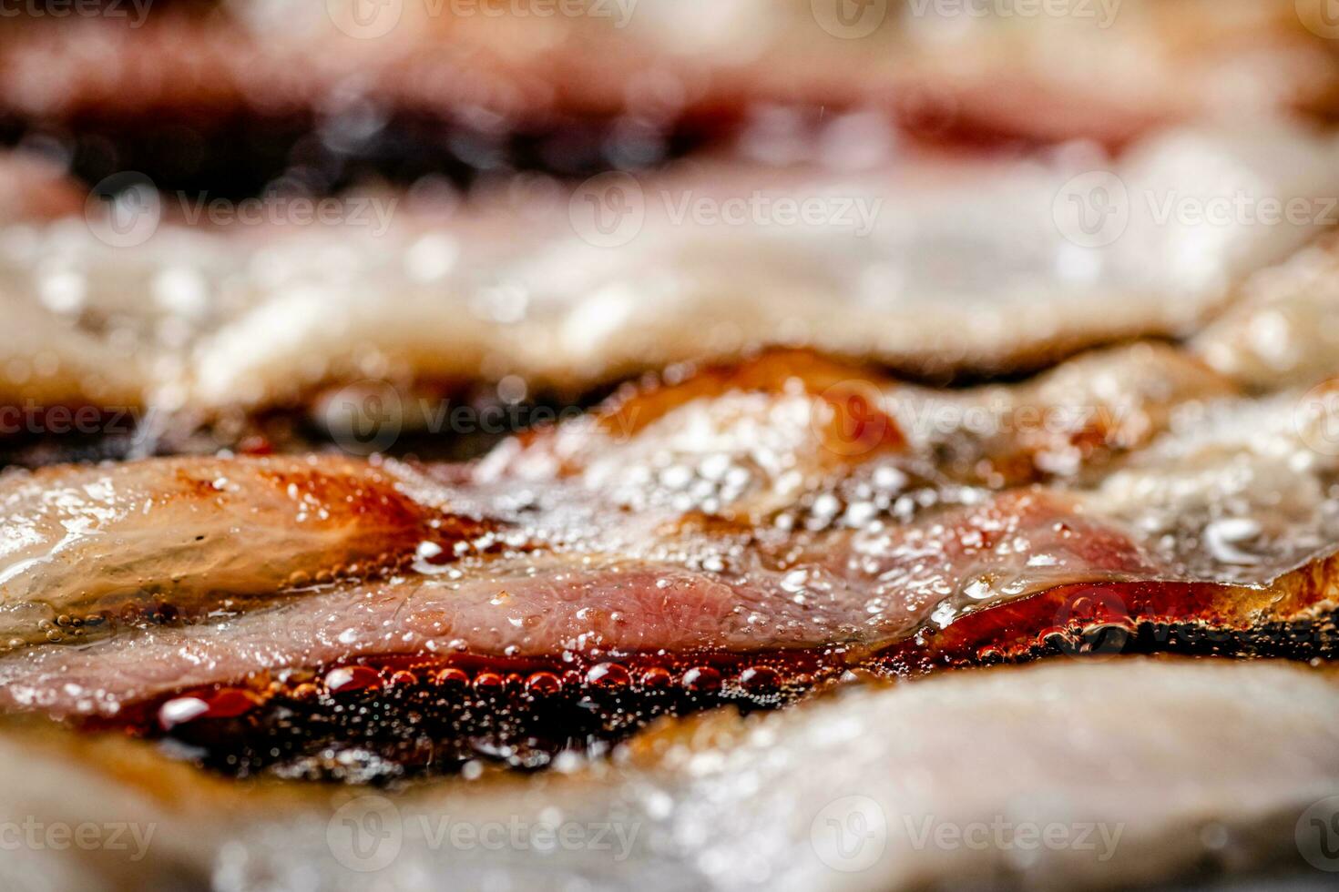 Pieces of bacon are fried in boiling oil with air bubbles. photo