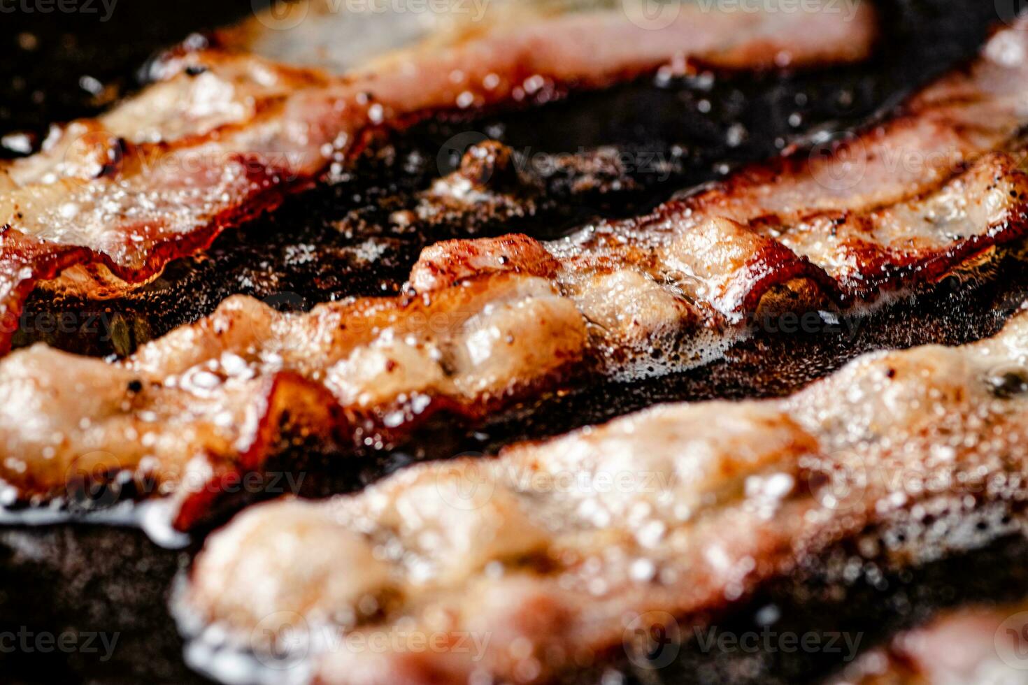 Pieces of bacon are fried in boiling oil with air bubbles. photo