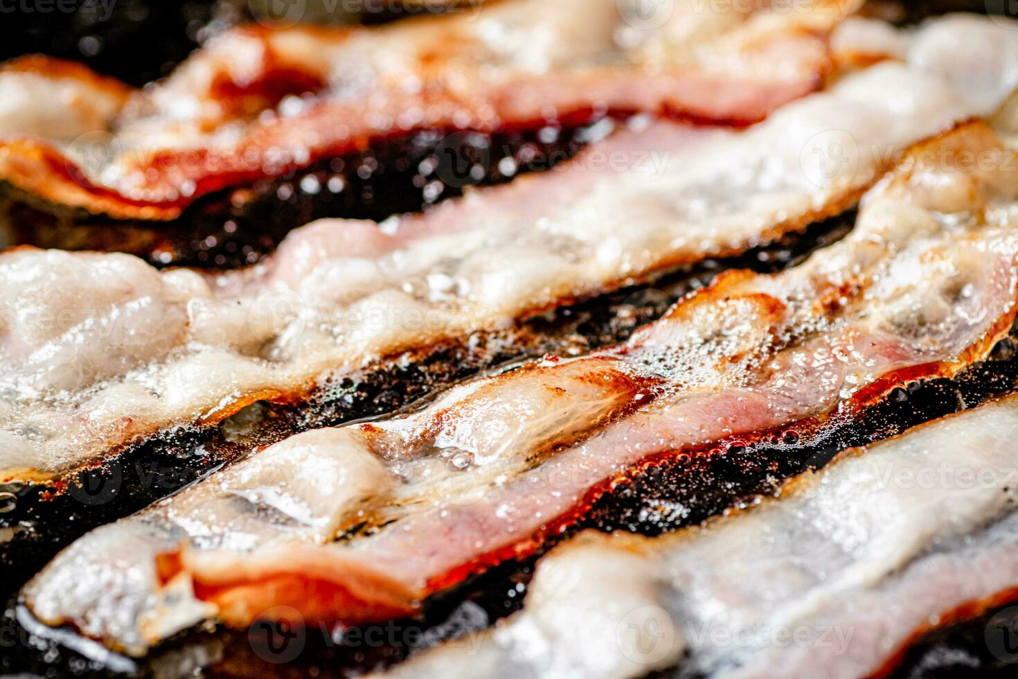 Pieces of bacon are fried in boiling oil with air bubbles. photo