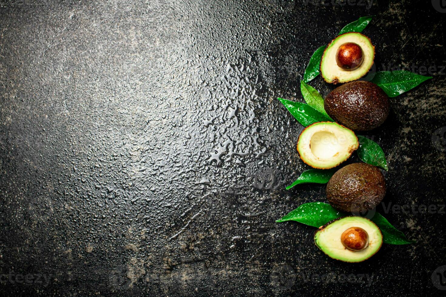 Fresh avocado with leaves. On a black background. photo