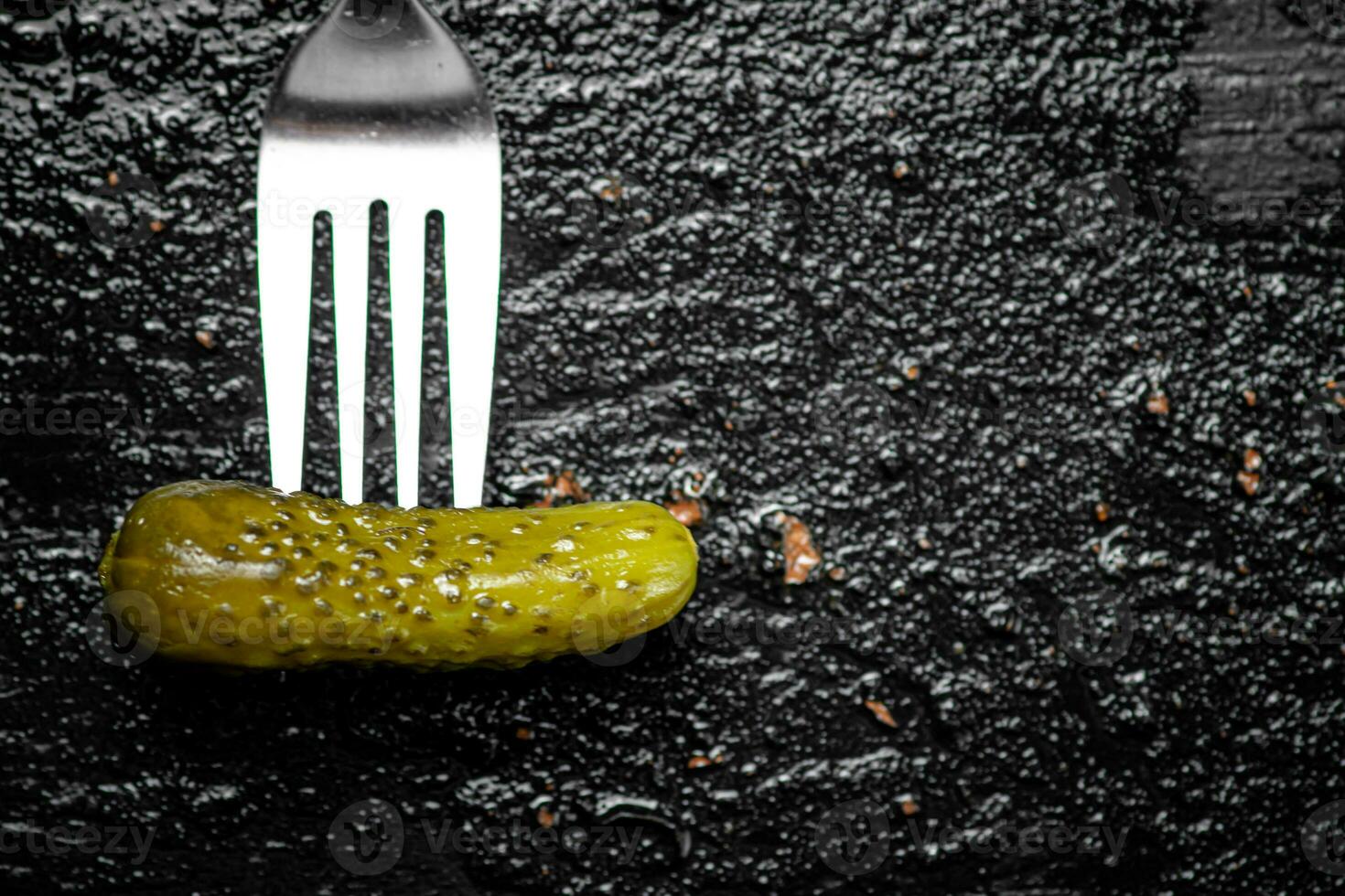 One pickled cucumber on a fork. photo