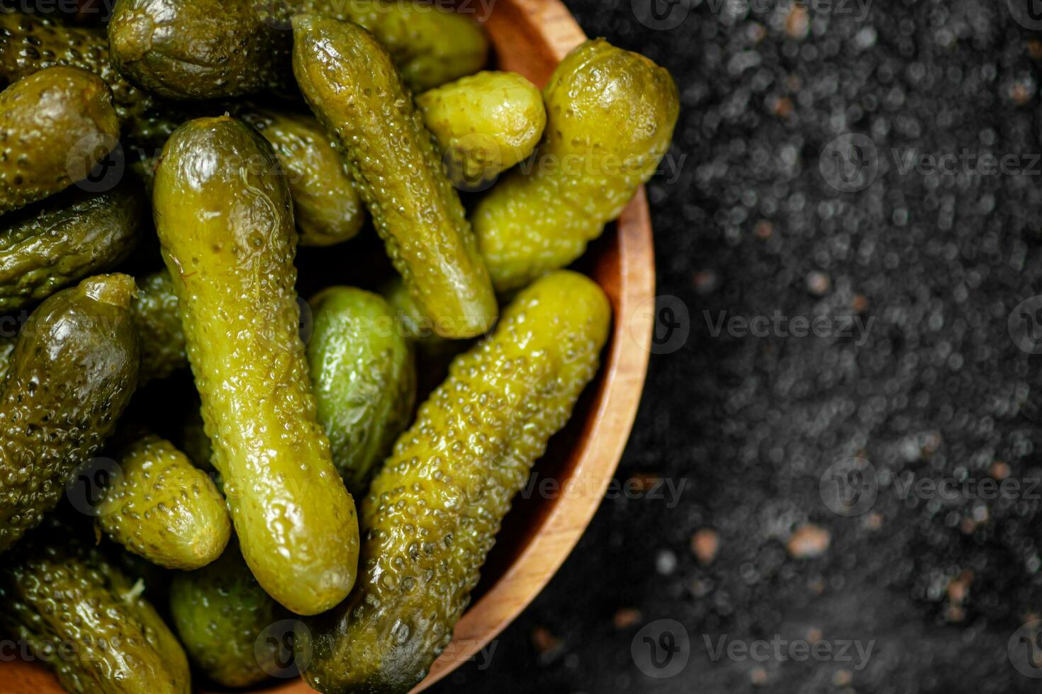 Wooden plate with pickles. On a black background. photo