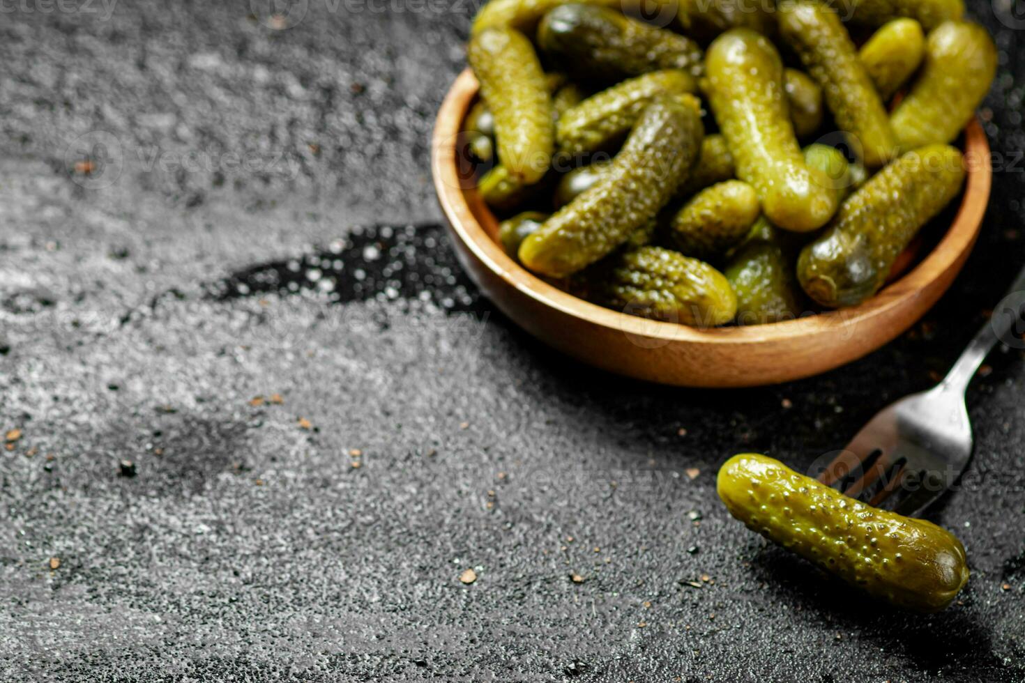 Wooden plate with pickles. On a black background. photo