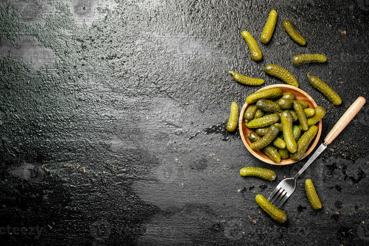 Wooden plate with pickles. On a black background. photo
