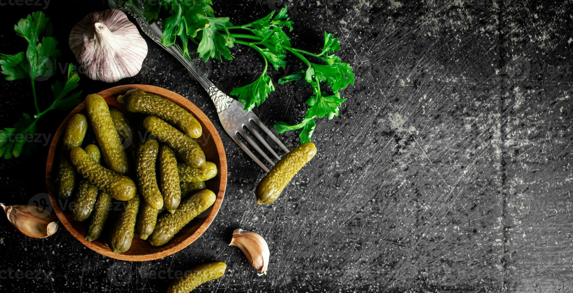 Wooden plate with pickles. On a black background. photo