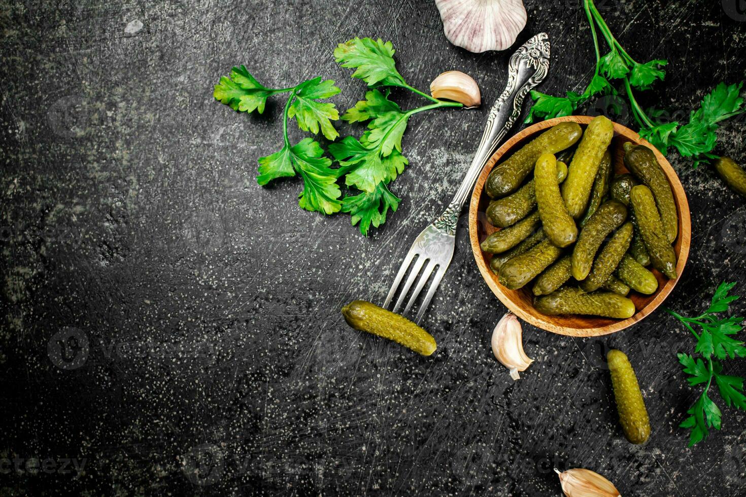 Wooden plate with pickles. On a black background. photo