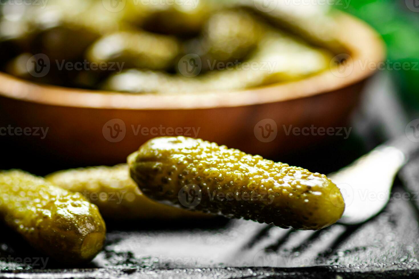 Wooden plate with pickles. On a black background. photo