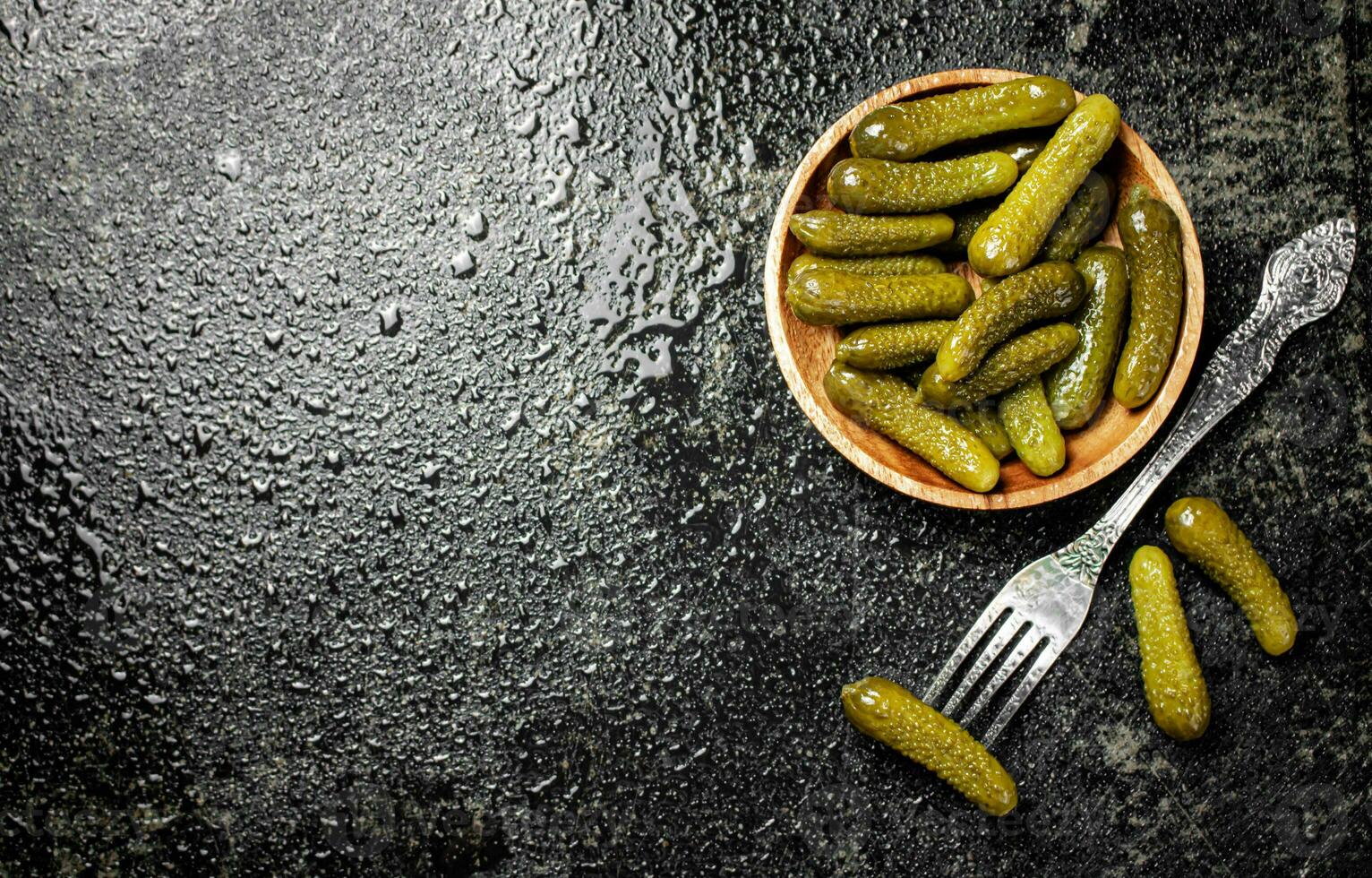 Wooden plate with pickles. On a black background. photo