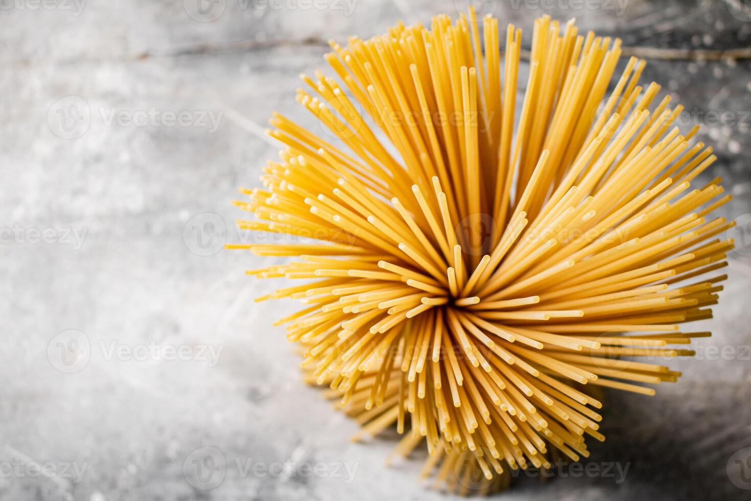 A bundle of spaghetti dry tied with a rope stands on the table. photo