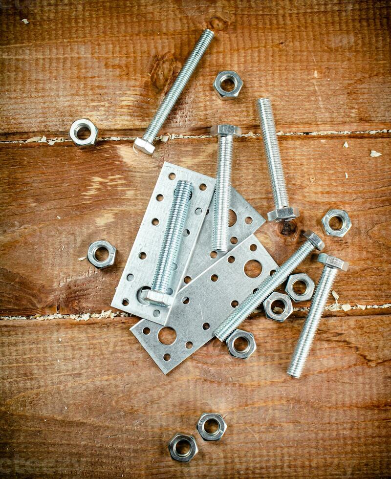 Metal plates for fastening. On a wooden background. photo