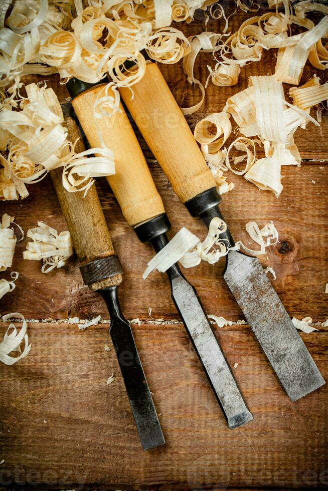 Chisels with wooden shavings. On a wooden background. photo
