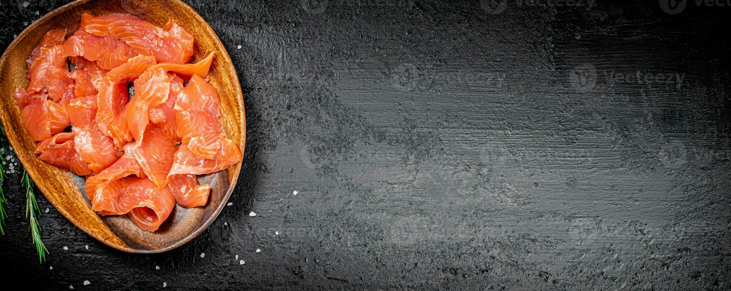 A wooden plate with slices of salted salmon. photo