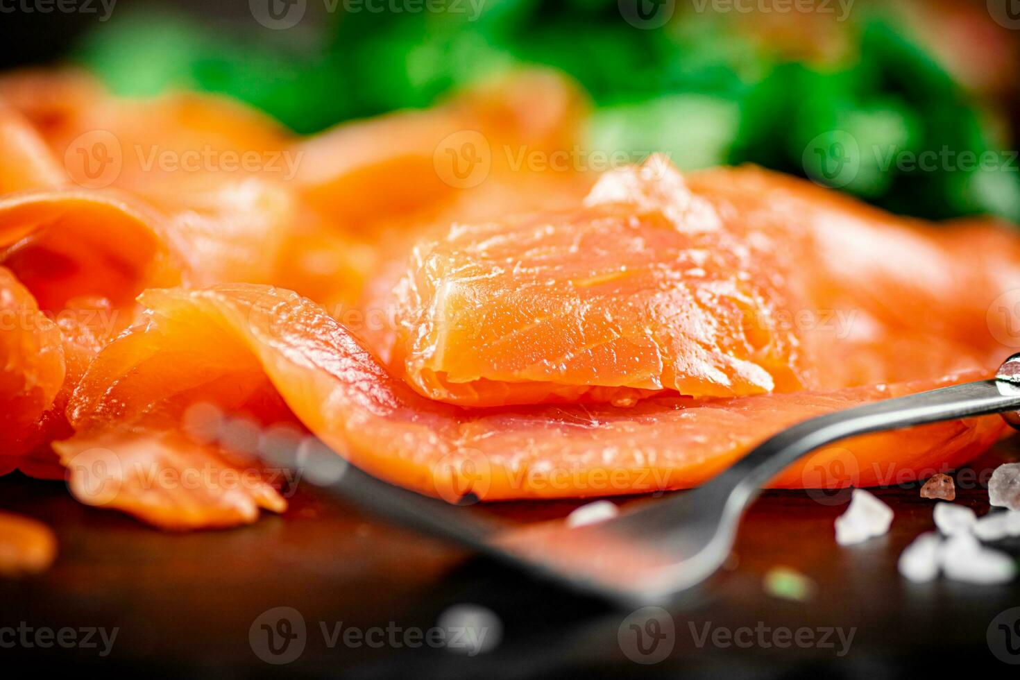 Pieces of salted salmon with greenery on a stone board. photo