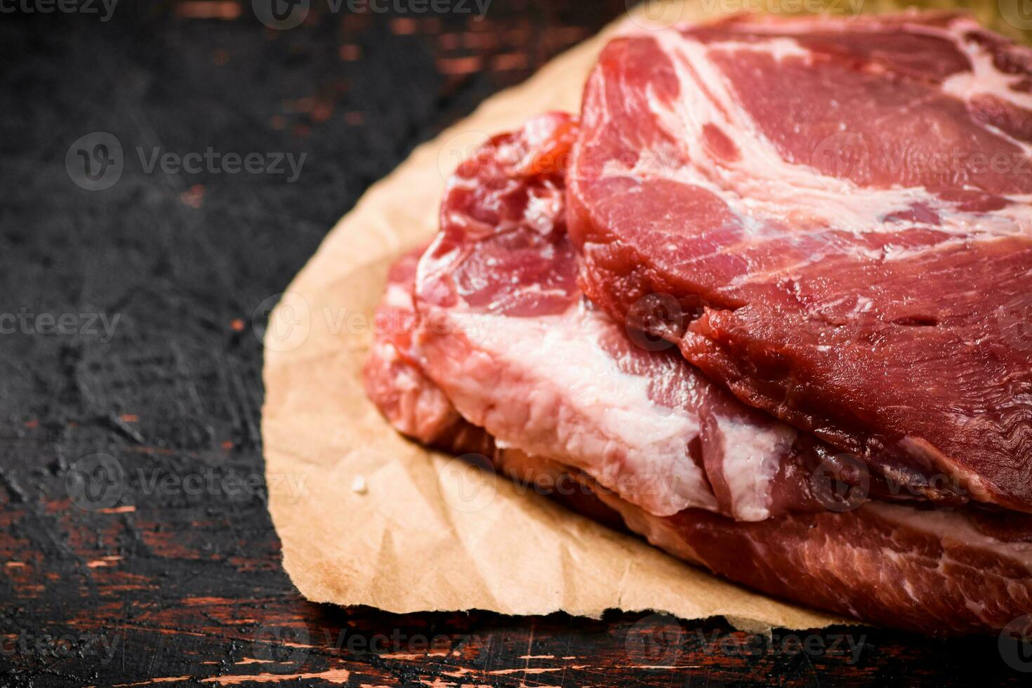 Raw pork steak on paper on the table. photo