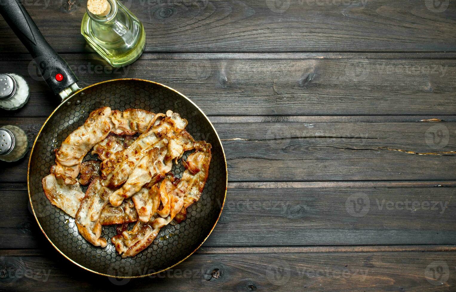 Fried bacon in a pan with spices. photo