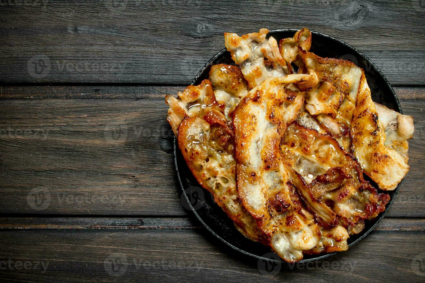 Fried bacon in a pan with spices. photo