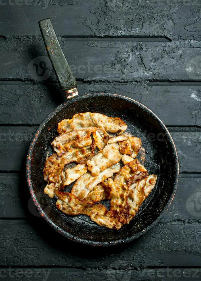 Fried bacon in a frying pan. photo