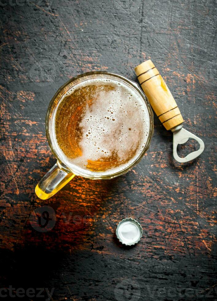 cerveza en un vaso taza y abrelatas. foto