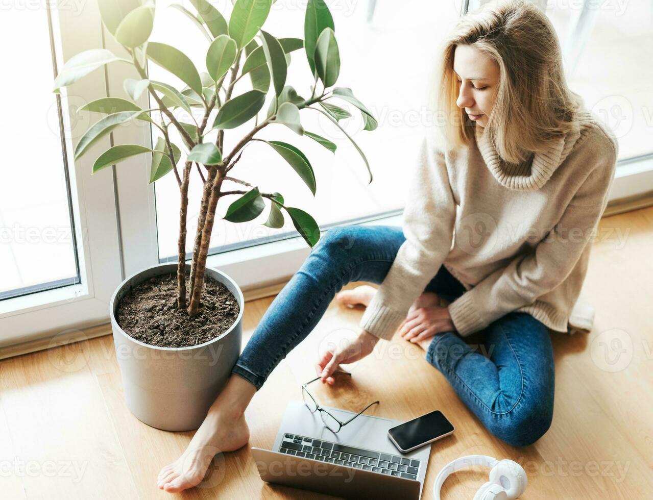 Young woman using her laptop while sitting on the floor at home. photo