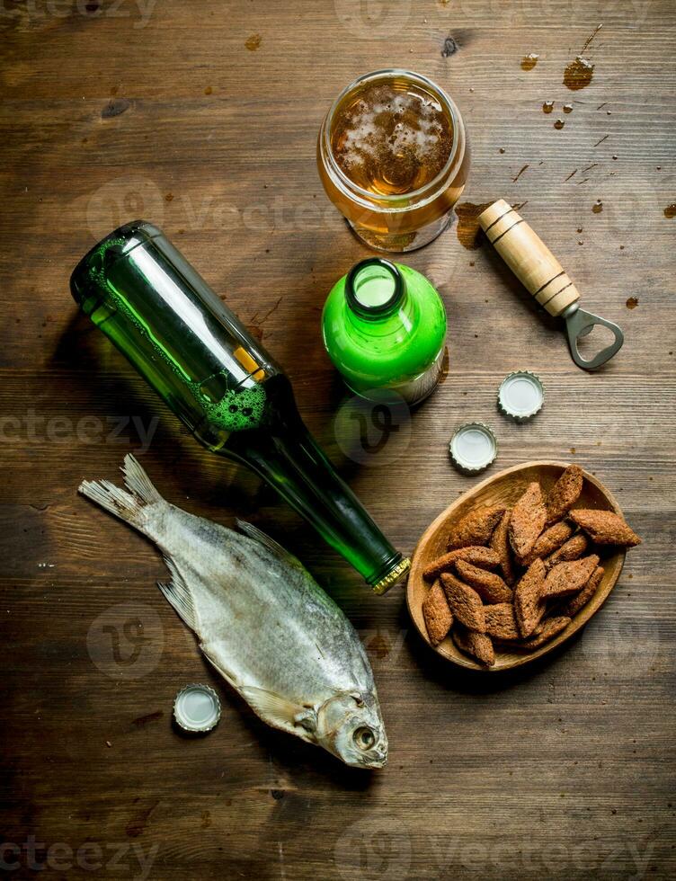 Beer with crumbs in bowl and dried fish. photo