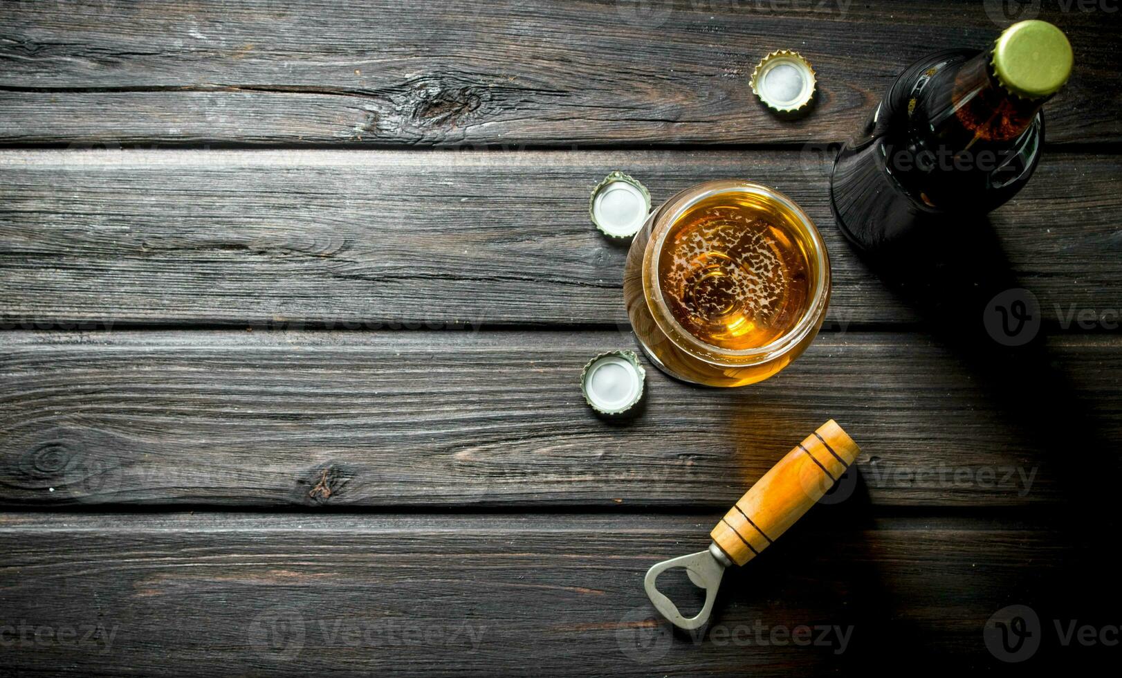 Beer in a glass and a bottle with opener and covers. photo