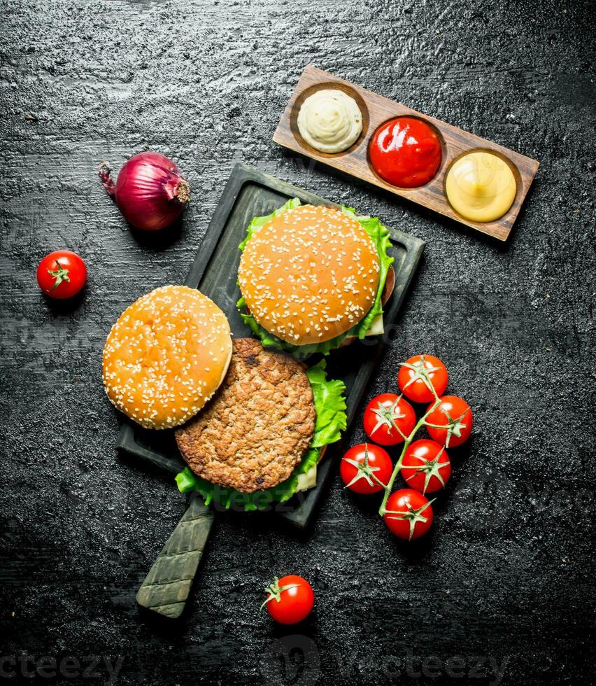 Burgers with tomatoes,sauces and onions. photo