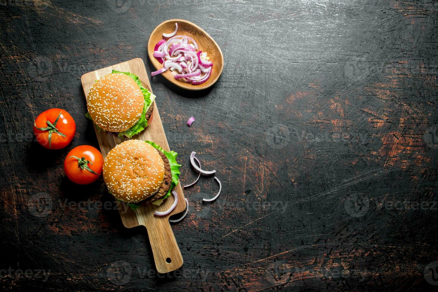 Burgers on the cutting Board and onion slices in the bowl. photo