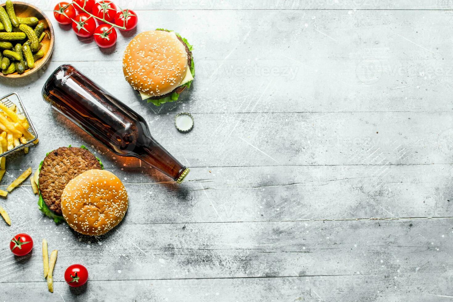 Burgers with beer in a bottle,gherkins and fries. photo