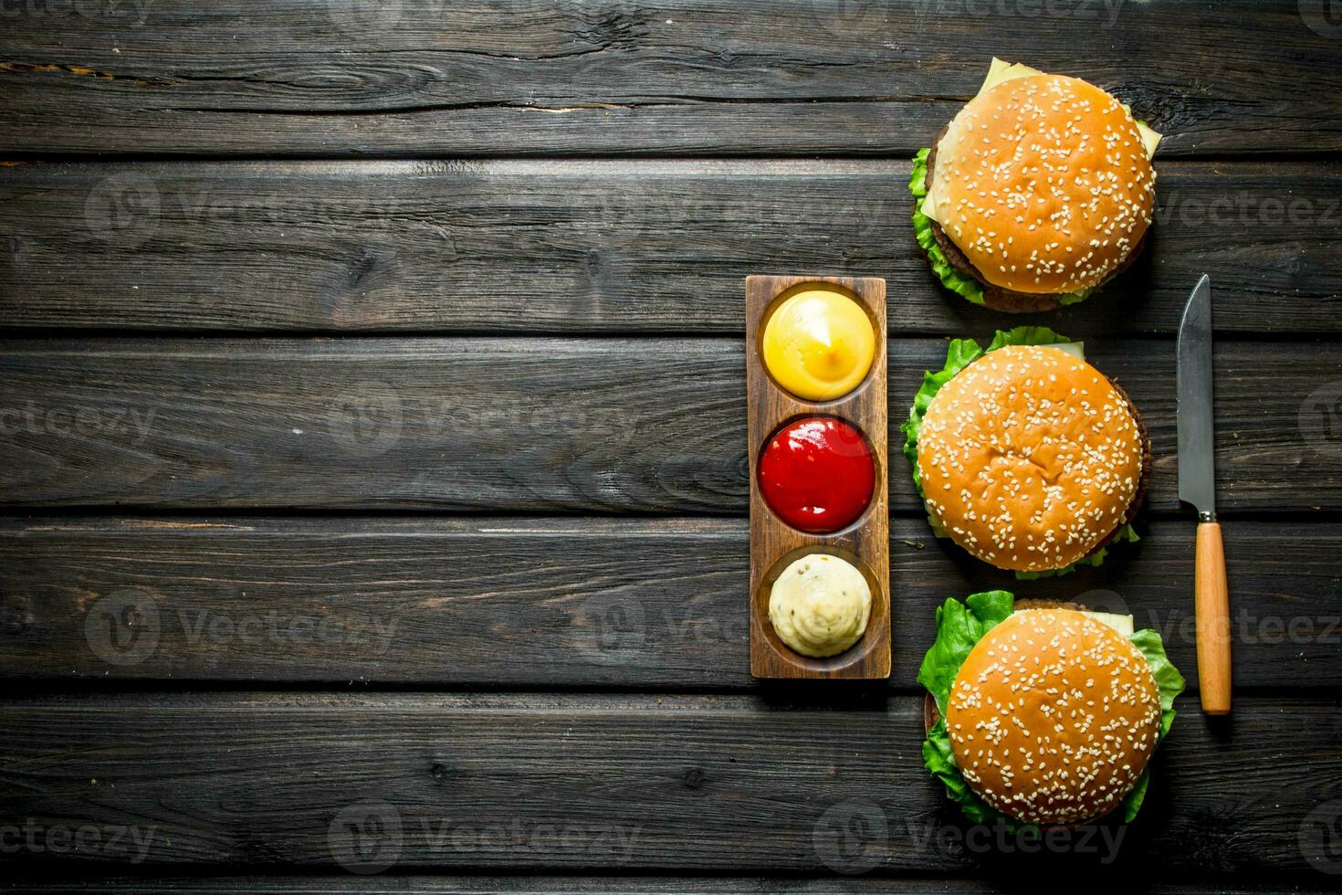 Burgers with different sauces and a knife. photo