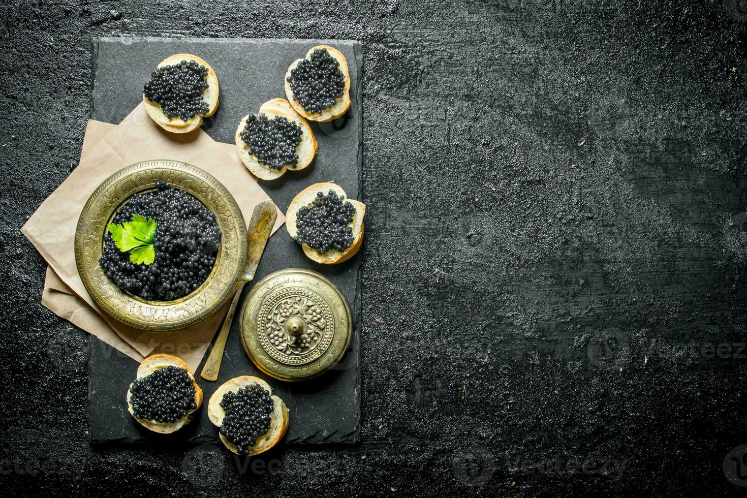 Sandwiches with black caviar and caviar in a bowl on paper with parsley. photo