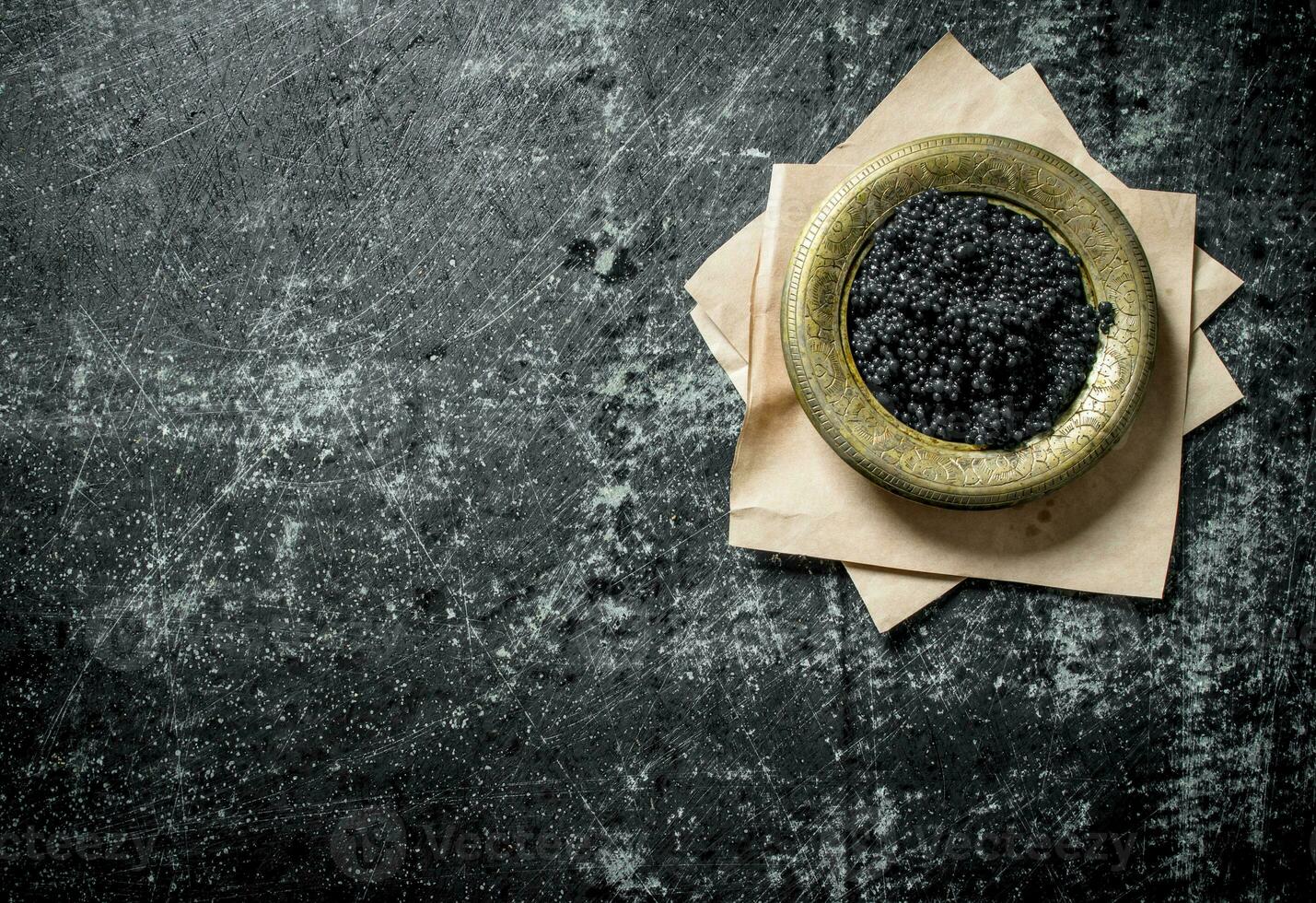 Black caviar in a bowl on paper. photo
