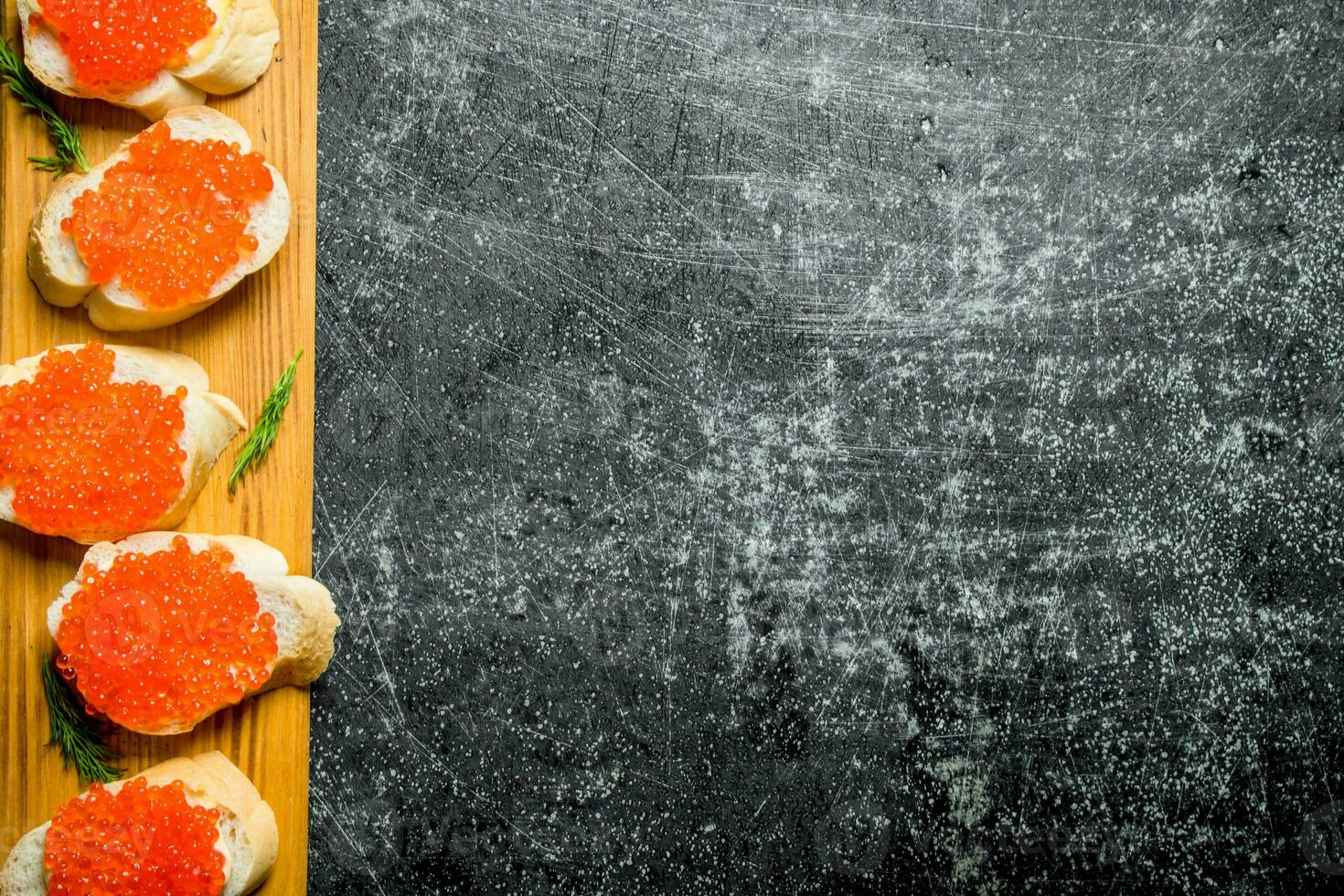 Sandwiches with red caviar on a wooden stand. photo