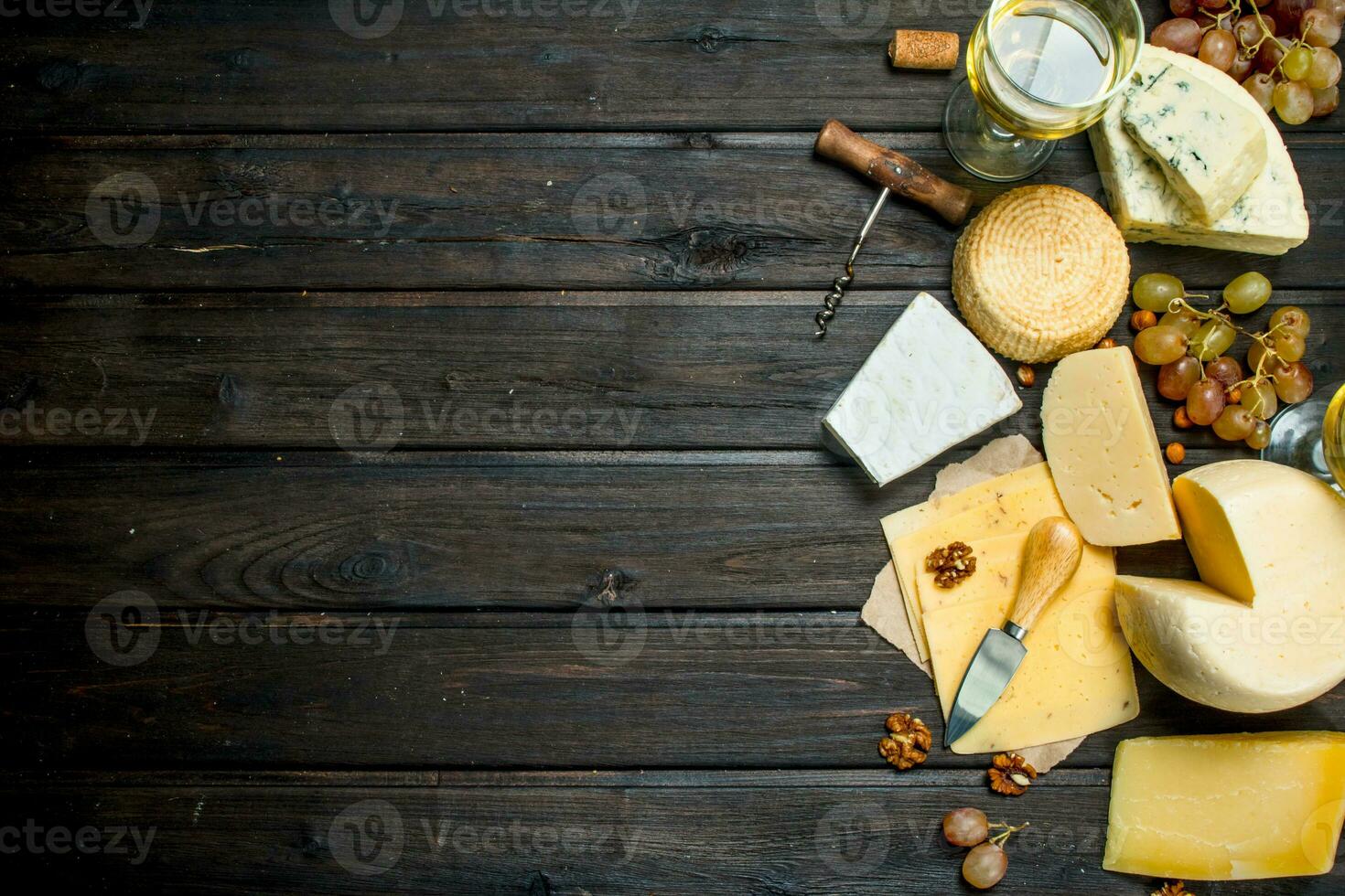 Assortment of different types of cheese with grapes and white wine. photo