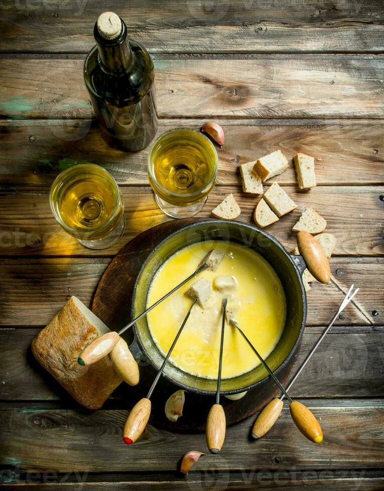 Delicious fondue cheese with bread slices and white wine. photo