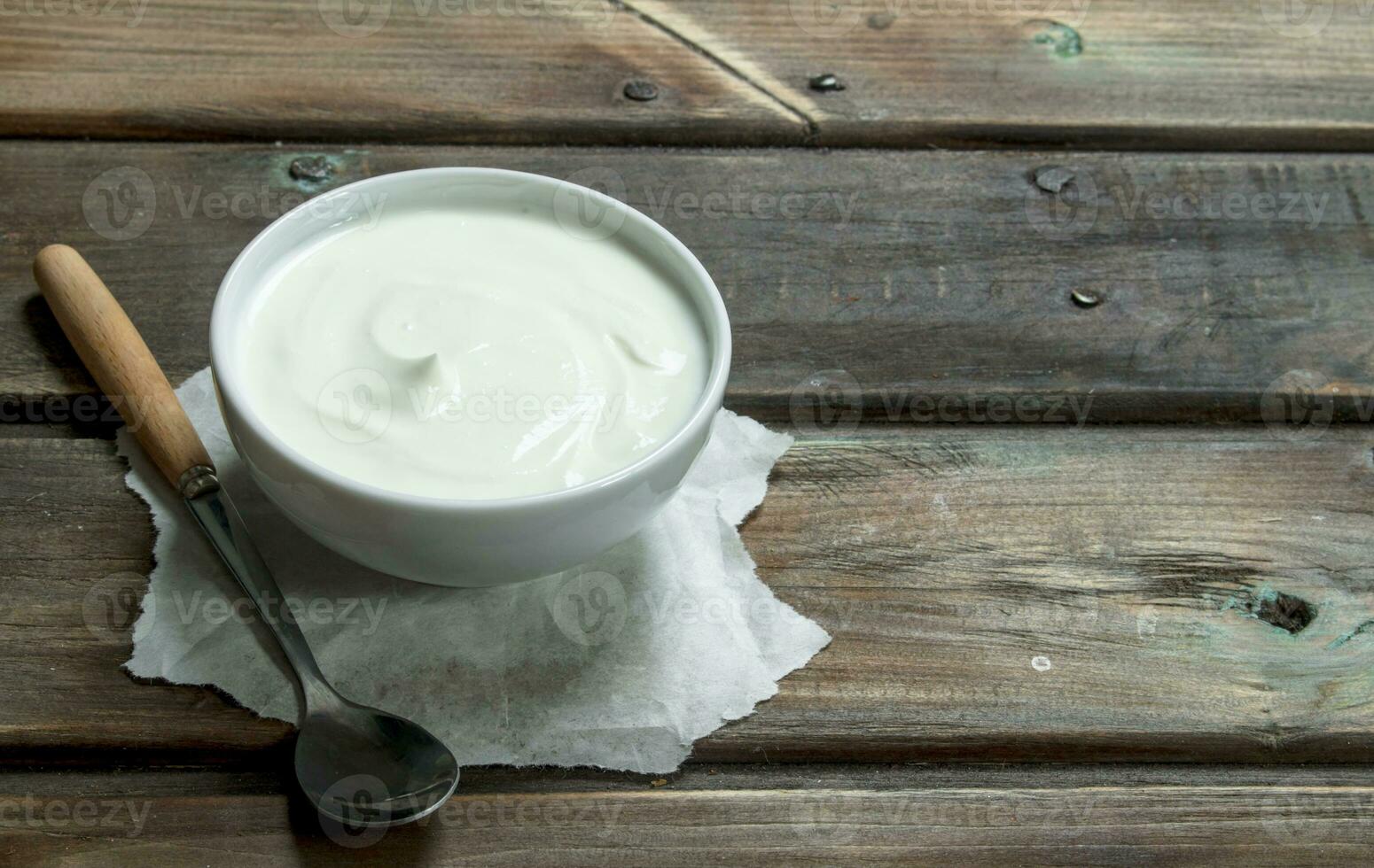 Fresh sour cream in bowl with spoon . photo