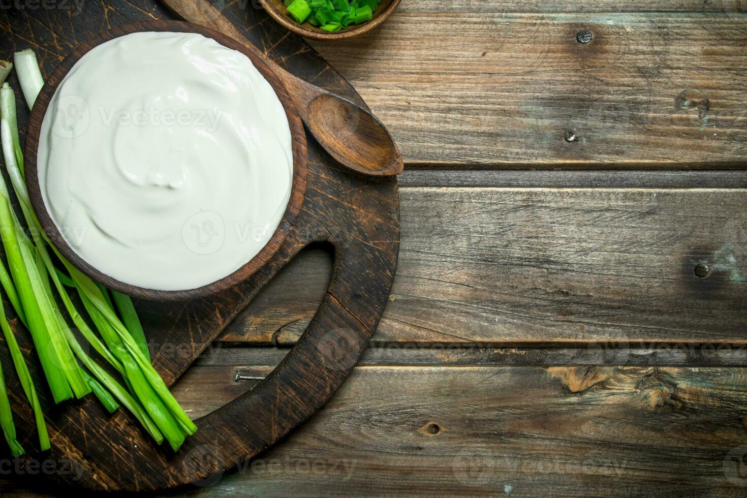 Fresh sour cream in bowl with green onions . photo