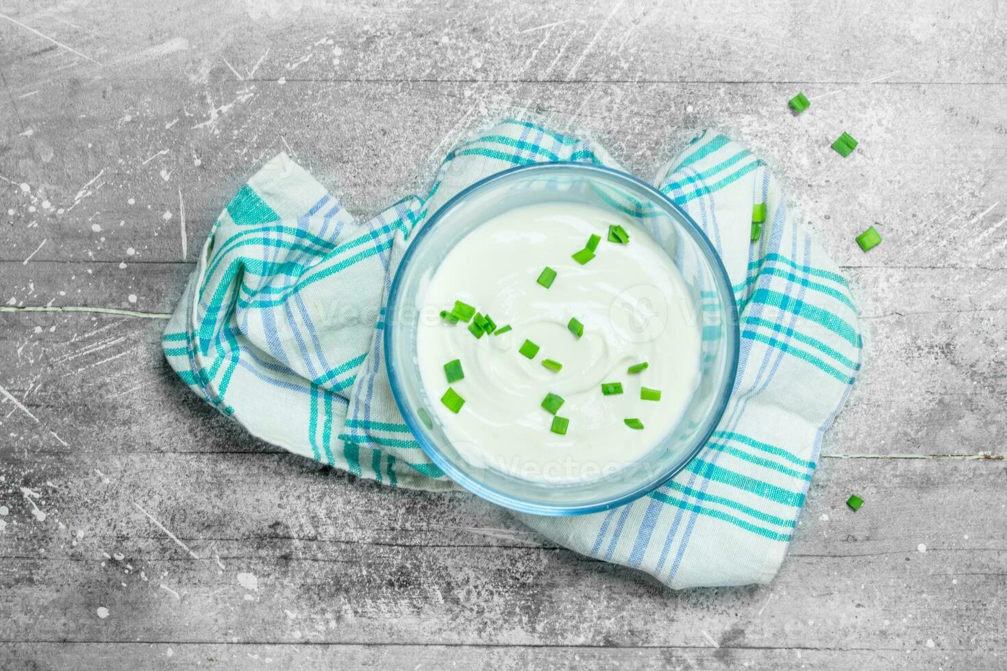 Sour cream in bowl with green onions. photo