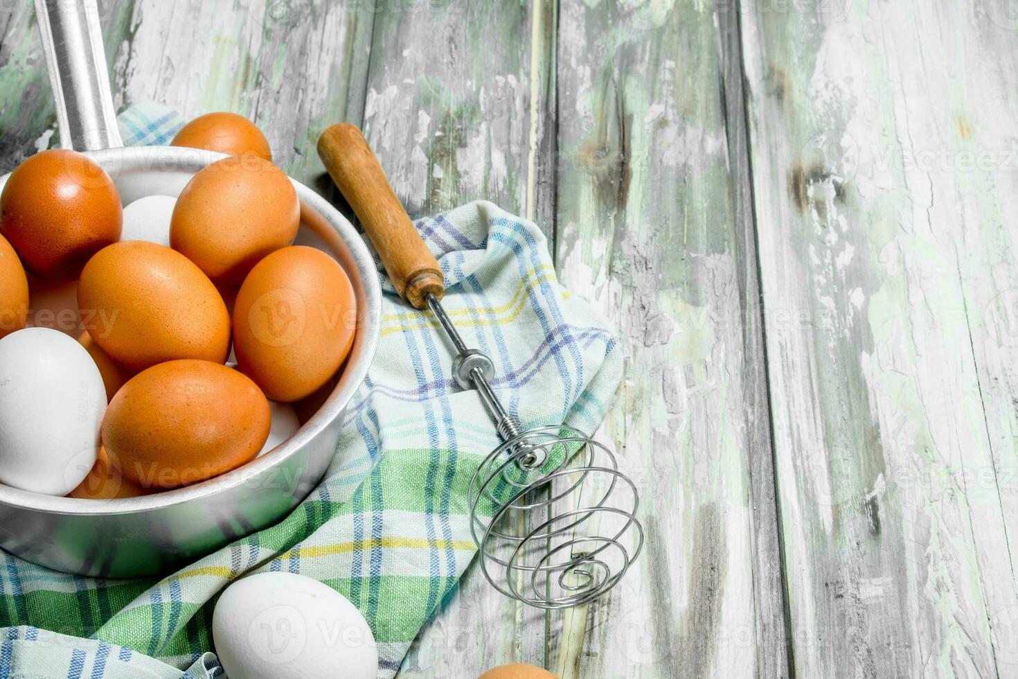 Eggs in a saucepan with a whisk on napkin. photo