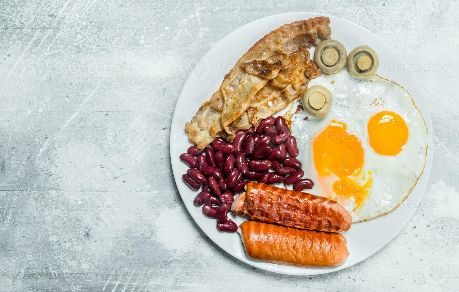 English breakfast. Fried eggs with sausages, bacon and beans. photo
