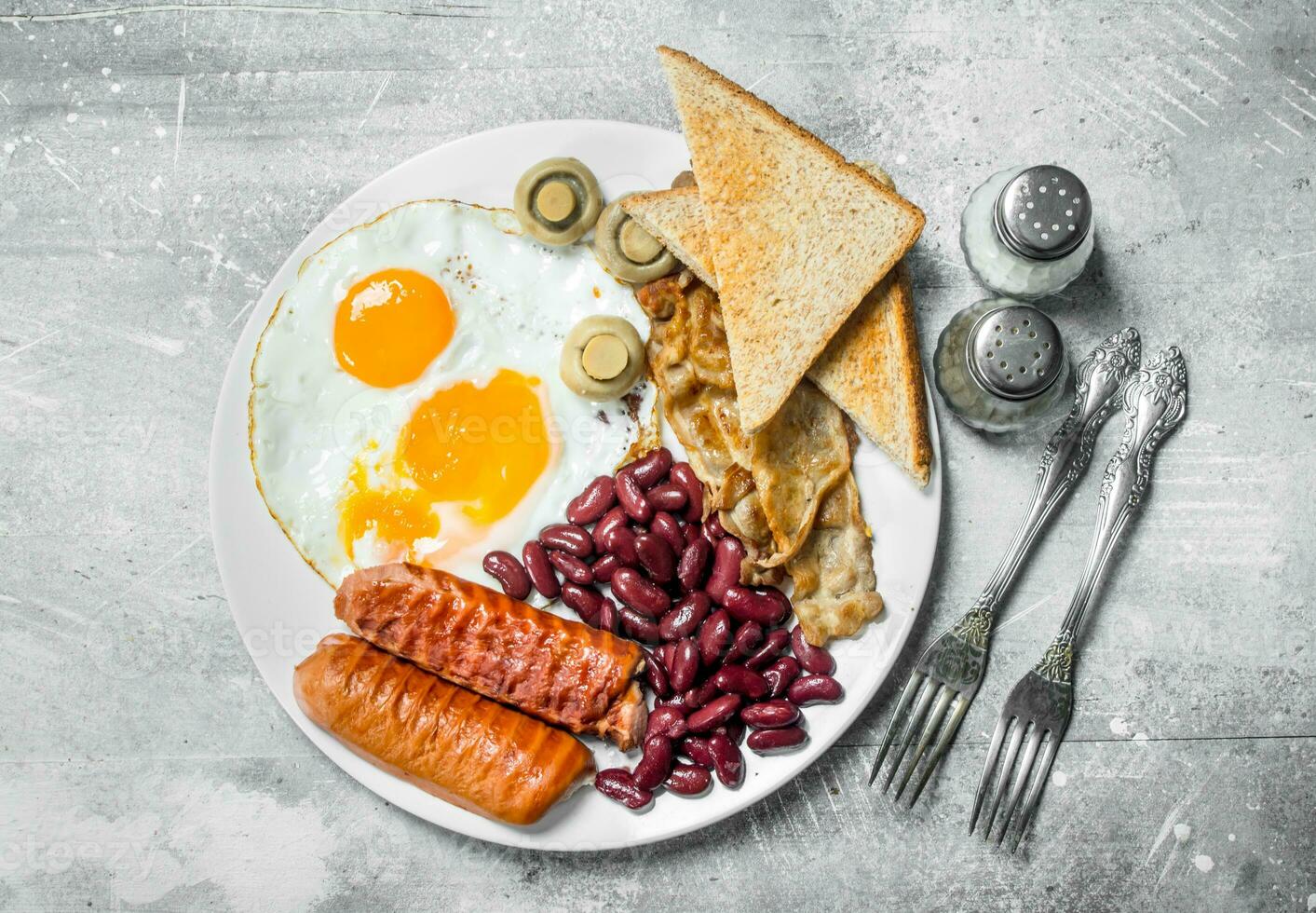 English breakfast. Fried eggs with sausages, bacon and beans. photo