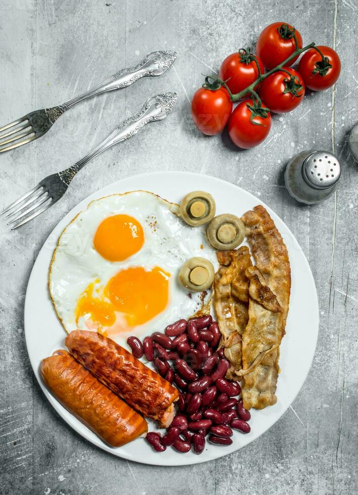 English breakfast. Fried eggs with sausages, bacon and beans. photo