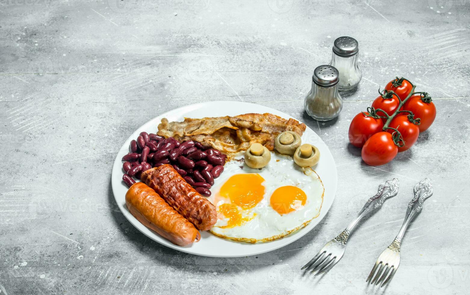 English breakfast. Fried eggs with sausages, bacon and beans. photo