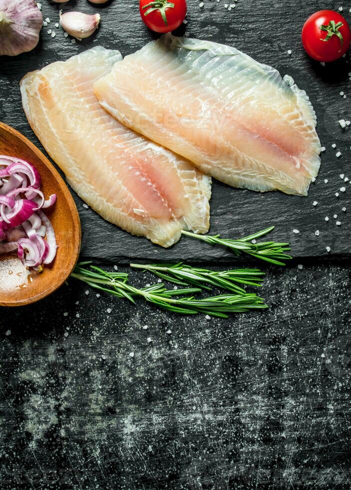 Fish fillet with chopped onion in bowl, garlic and rosemary. photo