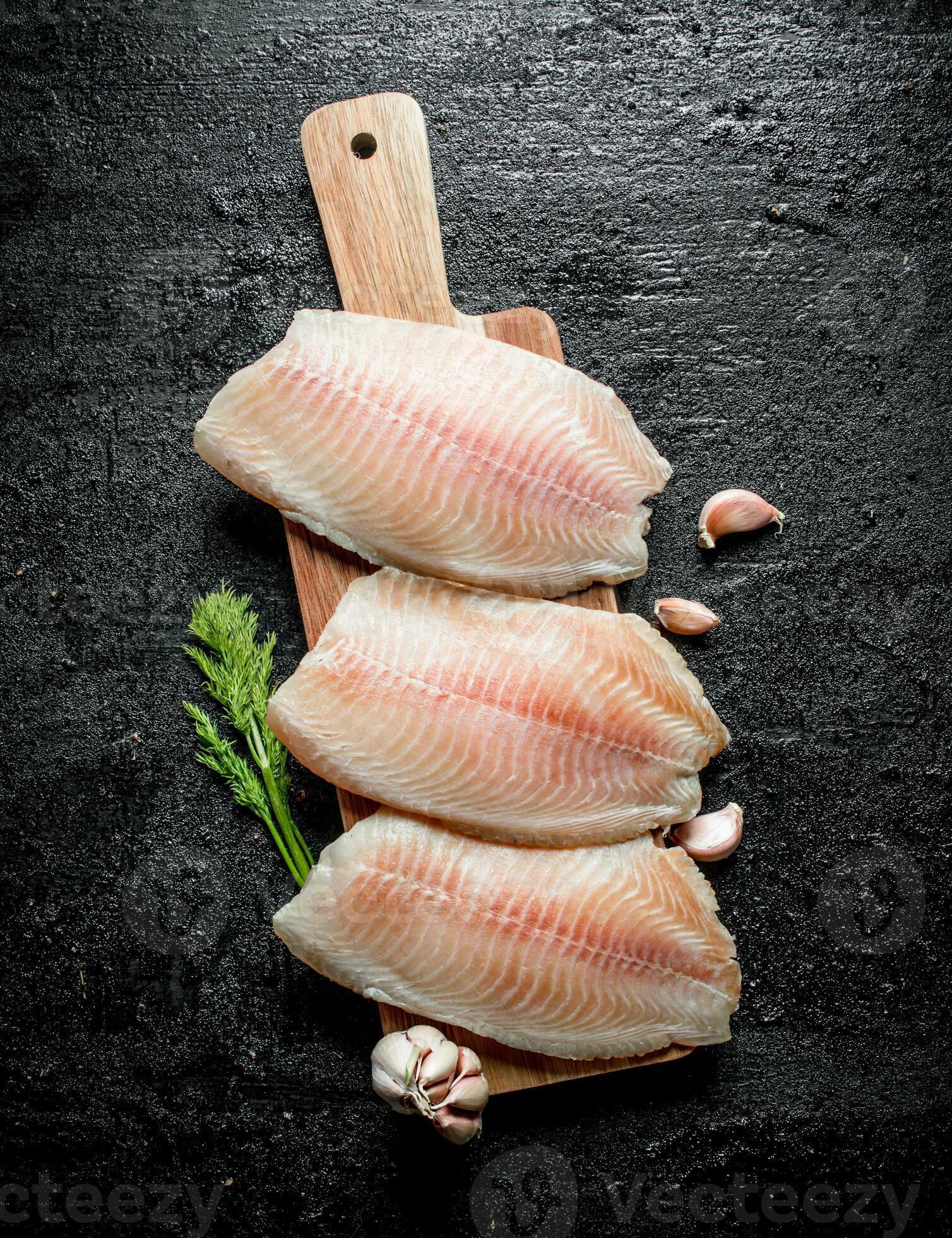 https://static.vecteezy.com/system/resources/previews/032/005/317/large_2x/fish-fillet-on-a-wooden-stand-with-dill-and-garlic-cloves-photo.jpg